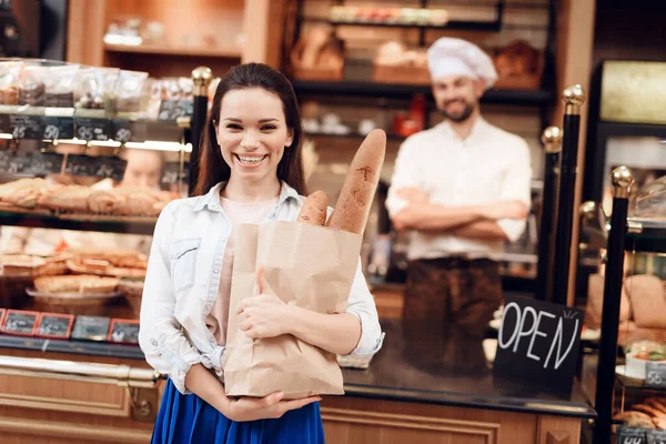 Jonge glimlachende vrouw koopt brood in de moderne bakkerij. — Stockfoto