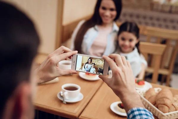 Junger Vater fotografiert Familie in Cafeteria. — Stockfoto