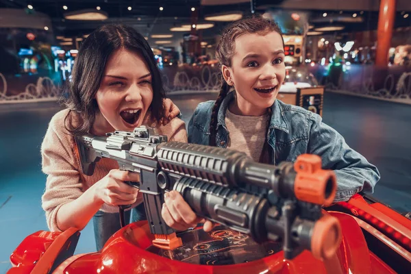 Daughter next to mother and watches as she plays.