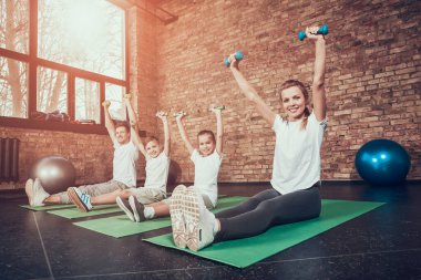 İnsanlar spor salonunda paspaslara oturup birlikte egzersiz yaparlar.. 