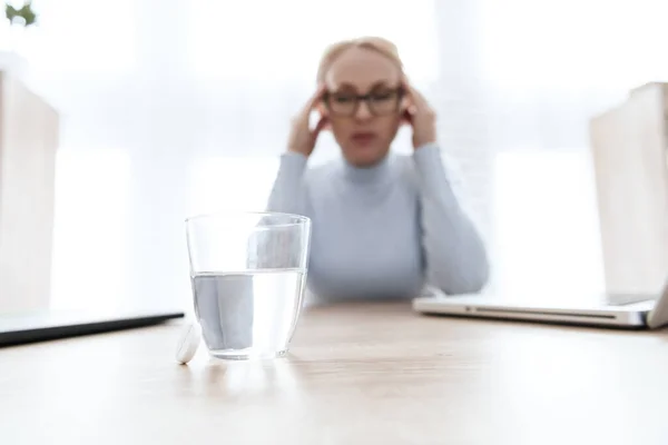 Un vaso de agua está sobre una mesa para niña enferma. — Foto de Stock