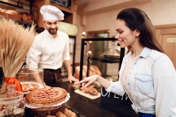 Young Man verkoopt brood aan klanten in de bakkerij. — Stockfoto