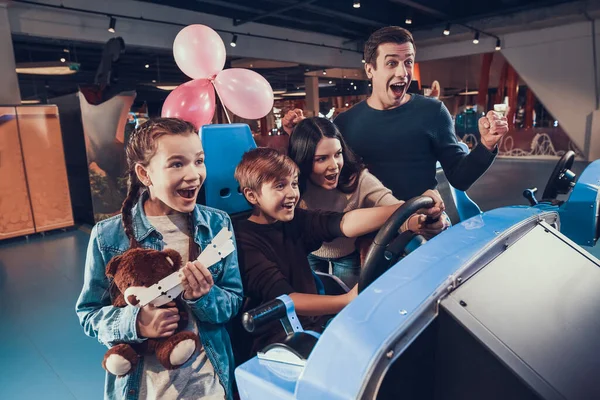 Mamá ayuda a su hijo a conducir un coche en un juego de ordenador. —  Fotos de Stock