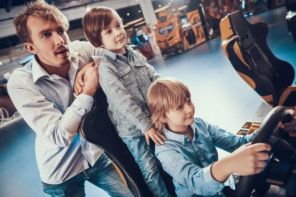 Dad and sons playing slot machines in center.