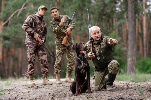 Hombre cazador señalando en algún lugar para perro de caza. — Foto de Stock