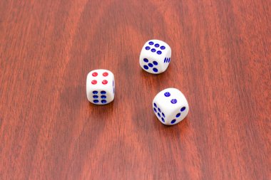 Three traditional six-sided dice on wooden surface