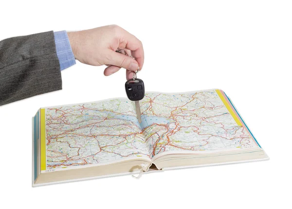 Mannenhand met autosleutels via een open road atlas — Stockfoto