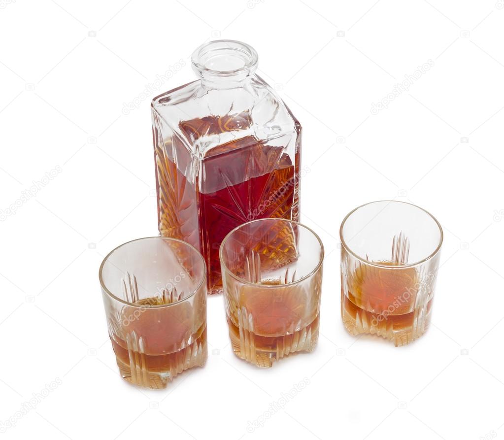 Decanter and three glasses with whiskey on a light background