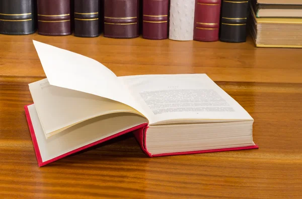 Open boek op houten oppervlak tegen de achtergrond van andere boeken — Stockfoto