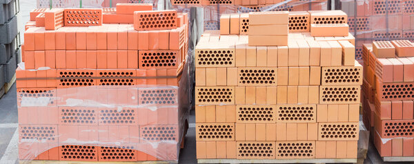 Pallets of perforated yellow and red bricks on warehouse