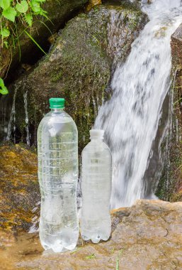 İçme suyu dağ dere arka plan üzerinde iki şişe
