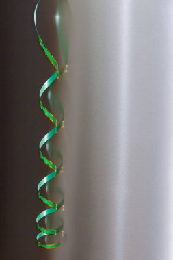 Yeşil kıvrımlı kağıt şerit ve altın renkler Matt metalinin yansıtıcı yüzeyinde asılı.