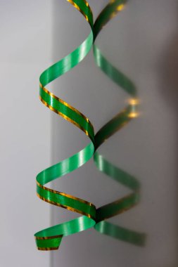 Yeşil kıvrımlı kağıt şerit ve altın renkler Matt metalinin yansıtıcı yüzeyinde asılı.