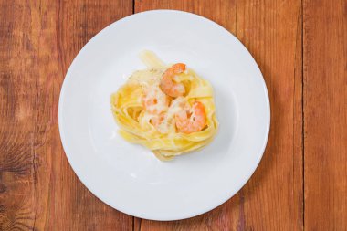 Erişteler yuvaya doluşmuş ve karides ve beyaz sosla pişirilmiş eski kırsal masada, üst manzara