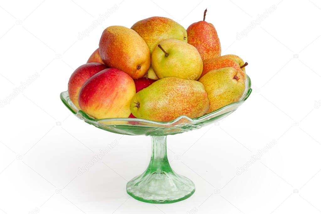 Washed pears and red apples covered with water drops in the vintage green glass vase for fruits on a leg on a white background