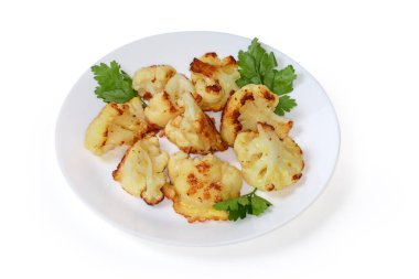 Hamur hamurunda kızartılmış ve beyaz arka planda maydanoz yapraklarıyla süslenmiş bir karnabahar parçaları.