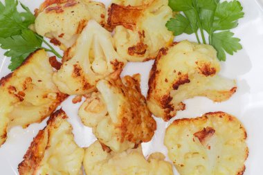 Beyaz karnabahar parçaları hamurda kızartılmış, tabağın yakın plan bir parçası.