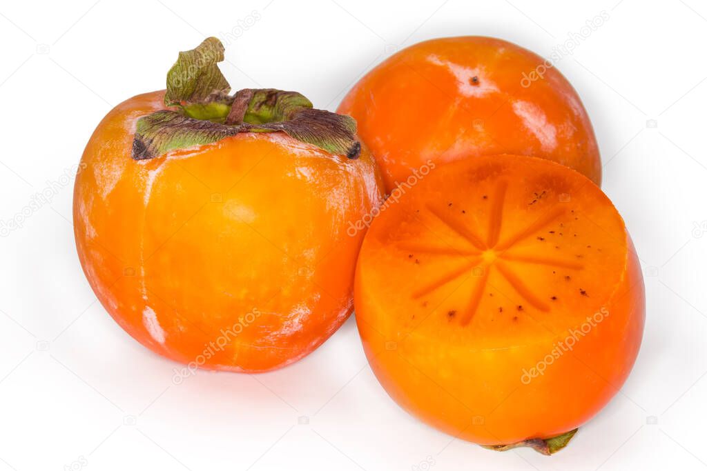Two whole and one cut across Diospyros kaki - variety of persimmon also known as Oriental persimmon or Sharon fruit on a white background, close-up in selective focus