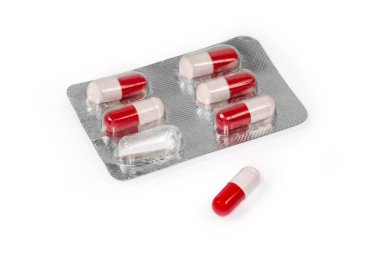 Kırmızı-beyaz haplar şeklinde ilaç içeren su toplayıcı paketi beyaz arka planda, seçici odak noktasında ayrı ayrı aynı haptır.