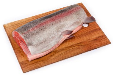 Kafası ve kuyruğu olmayan taze bir gökkuşağı alabalığının bağırsakları deşilmiş bir parçası beyaz arka planda tahta kesme tahtasındaki balık pullarından soyulmuş.