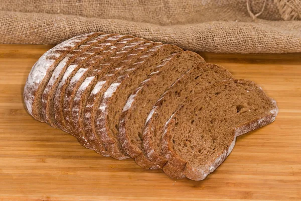 用小麦和黑麦面粉在木制表面切碎了一半的烤面包 — 图库照片