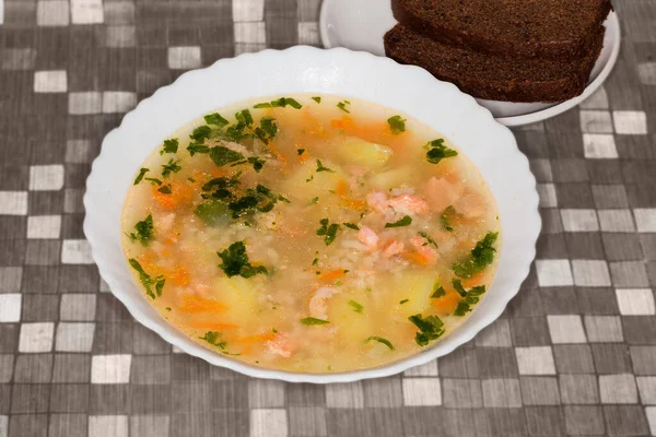 Rainbow trout clear soup with chunks of fish in the white bowl, brown bread on a table — Stock Image Rainbow Trout Clear Soup Chunks Fish White Bowl Brown Bread Royalty Free Stock Images