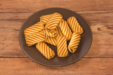 Çerezler flüt tüpleri şeklinde eski bir kırsal masada kahverengi bir tabakta reçel dolu.