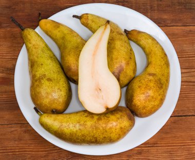 Konferansın olgun armutları. Sarı, kahverengi renkli. Beyaz bir tabakta, eski bir kırsal masada.