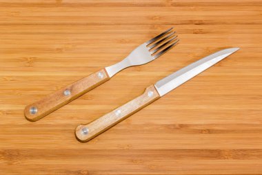 Çatal bıçak seti paslanmaz çelik çatal ve bıçak ile bambu ahşap bir yüzey üzerinde ahşap saplar, üst görünüm