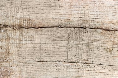 Çatlaklarla kaplı eski ahşap bir tahtanın yüzeyi, ahşap haşarat izleri ve zamanla, dokularla, arka planla kararmış.