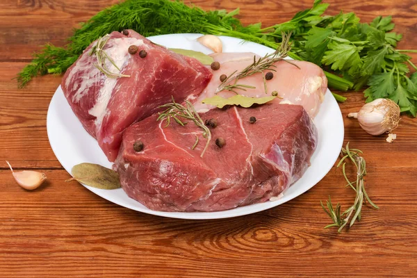 骨なしの豚肉と牛肉 スパイスと古い素朴なテーブルの上に緑の間で白い皿の上に鶏の胸肉の作品 — ストック写真