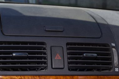 Hava akışı saptırıcıları ve acil durum düğmeleri olan havalandırma delikleri. Arabanın iç kısmı seçici odak noktasında yakın plan