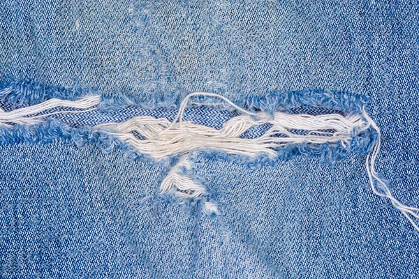 Gat Een Oude Gescheurde Blauwe Jeans Met Gerafelde Draden Stof — Stockfoto
