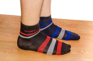 Bir çift siyah çorap, erkek bacağındaki süsün farklı renginde, tahta zeminde beyaz bir arka plana karşı.