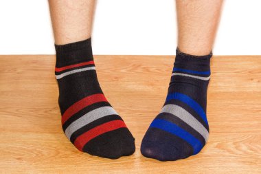 Bir çift siyah çorap, erkek süslemelerinin farklı renginde. Ahşap zeminde beyaz bir arka plana karşı ayaklar.