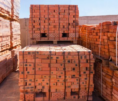 İç yapıların kullanımı için kırmızı tuğlalar inşa ediliyor. Açık hava deposundaki ahşap paletlere inşaat yapılıyor.