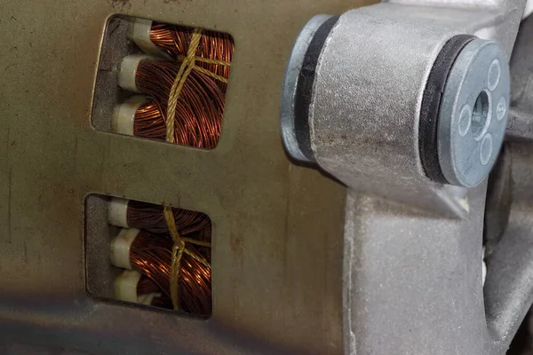 Kapağında havalandırma delikleri olan elektrikli bir motor parçası. Bu parçanın içinden sarkaçlar ve şok emici motor ön planda görülebilir. Seçici odak noktasında yakın plan.