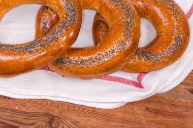 Geleneksel Doğu Avrupa halkası şekilli ekmek ruloları haşhaş tohumları serpiştirilmiş eski bir kırsal masa üzerindeki peçeteye serpiştirilmiş, yakın plan