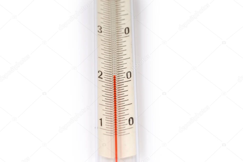 Fragment of a scale of alcohol glass thermometer with Celsius units and red liquid column in capillary on a white background, close-up in selective focus