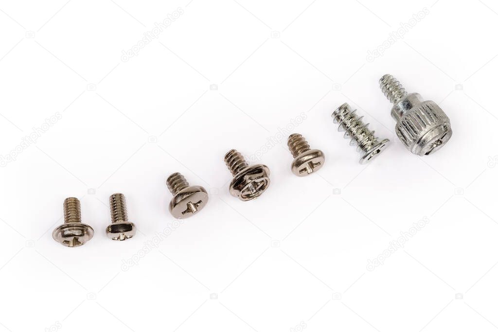 Different self-threading sheet metal screws and machine screw with cross recessed and combined heads and anti corrosion coating lined in a row on a white surface, top view close-up
