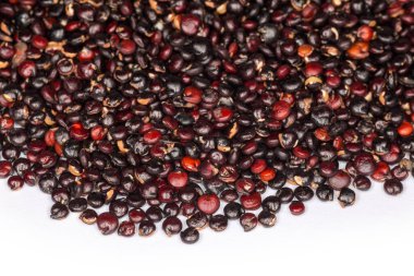 Beyaz bir yüzeyde ham kırmızı ve siyah kinoa tohumları, seçici odak noktasında yakın plan