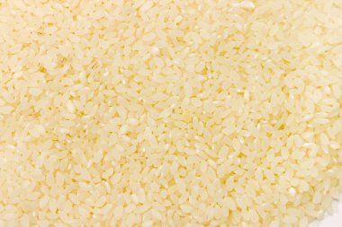 Pişmemiş kuru, kısa taneli, eşit dağılmış beyaz pirinç. Üst taraf yakın plan, arka plan.