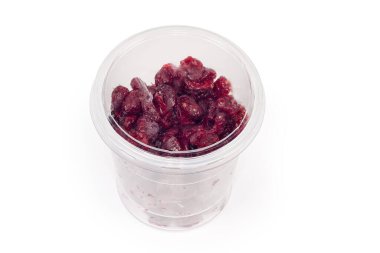 Dried cranberries in plastic food container in form of transparent cup with closed lid on a white background