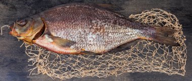 Salted and air-dried big bream on a black surface with part of fishing net