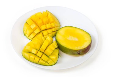 Fresh mango cut into pieces and halves prepared in the form hedgehog style on white dish on a white background