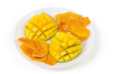 Dried slices of mango pulp and fresh mango halves cut in form the hedgehog style on white dish on a white background