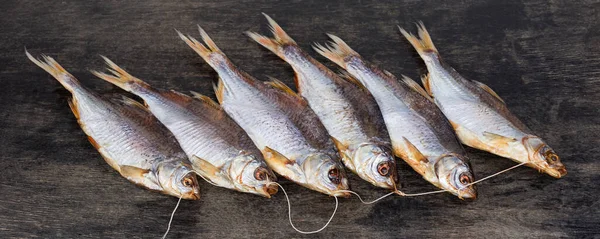 Bunch of salted and air-dried roach fish on a black surface