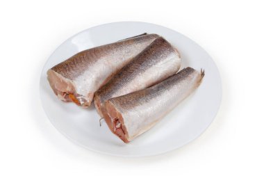 Kafası ve kuyruğu olmayan, beyaz bir arka planda beyaz bir tabakta balık pullarından temizlenmiş, pişmemiş Arjantin hake cesetleri.