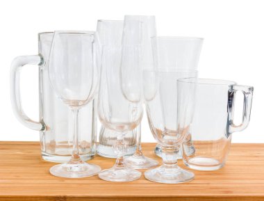 Beyaz arka planda bambu ahşap bir yüzey üzerinde çeşitli boş bira bardakları, şarap bardakları ve cam bardaklar.