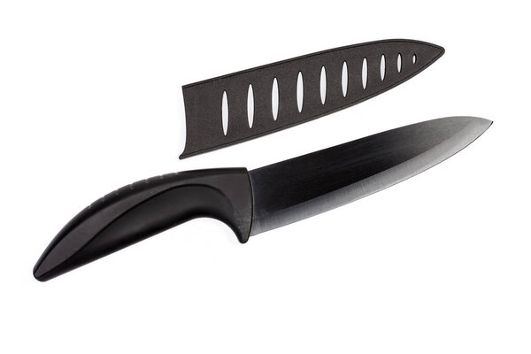 Многофункциональный кухонный нож с черной пластиковой ручкой, керамическое лезвие и удаленный пластиковый протектор лезвия на белом фоне, вид сверху